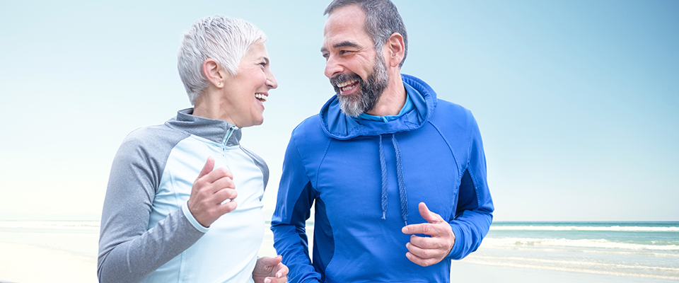 Older couple running outside in training gear