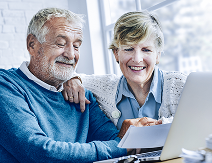 Older couple looking at notes in front of their desktop